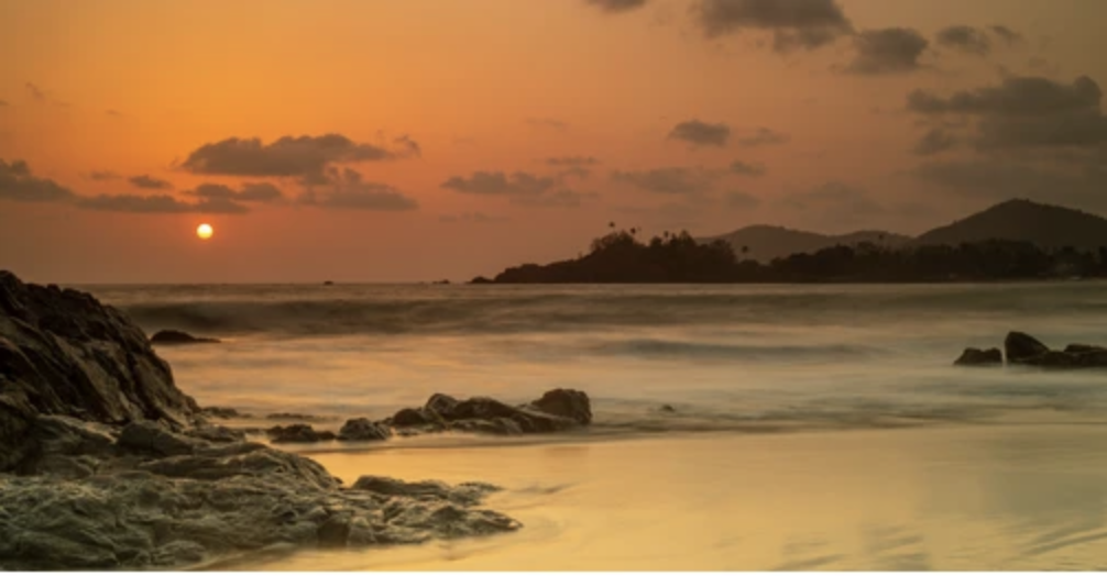 Golden sunset over the sea and rocks at Patnem Beach, South Goa
